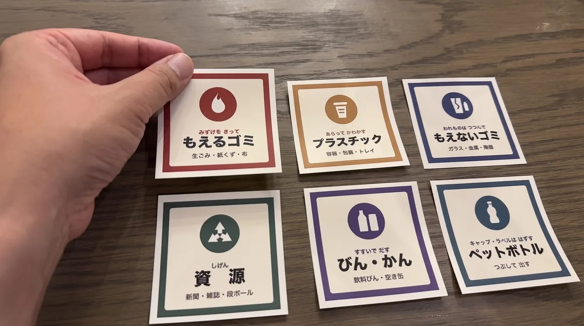 手に持った「もえるゴミ」シール。貼りやすい手のひらサイズ